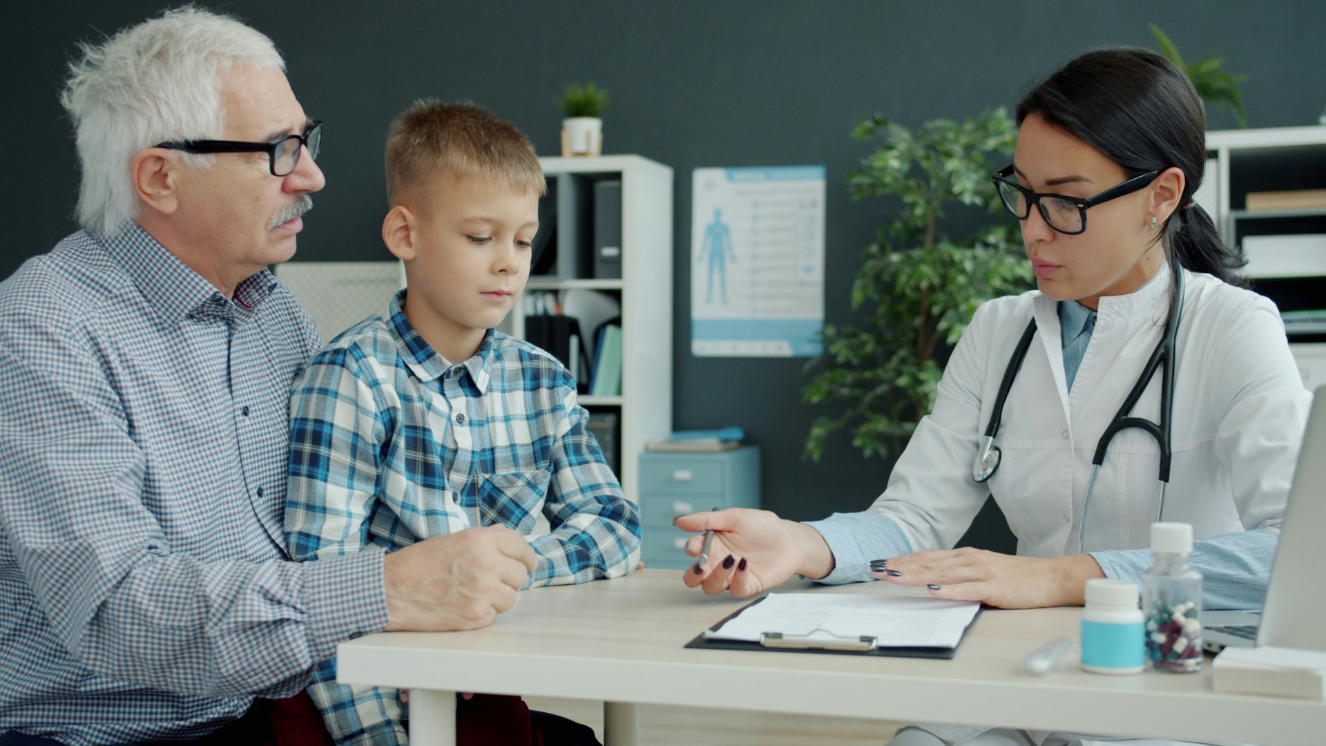 A clinician taking notes during a consult with a mother and young daughter.